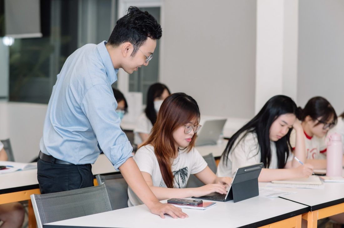 An 8020 SAT class: the tutor checks a student's work at her desk